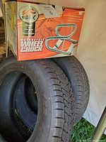 Stacked 4 black tires partially visible with a boxed new motorcycle wheel chock on top