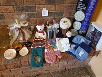 Full lot of Christmas items including a tree top angel, stuffed snowman, towels, CDs, cookie jar, and LED outdoor lights on fireplace mantle