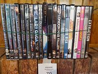 Front view of 21 DVDs lined up on a wooden shelf, titles including Michael Jackson, Lady Sings The Blues, and others.