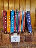 Photo showing complete set of Friends DVD seasons 1 through 10 with various colored cases standing upright on a brick surface.