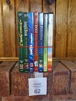 Front view of 9 Disney DVDs lined up vertically on a wooden shelf, titles clearly visible.