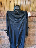 Full view of black superhero costume and mask hung on wall