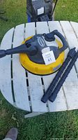 Photos of Sprinter Sistema pressure washer surface cleaner with two black rotary spray arms on white table outside.
