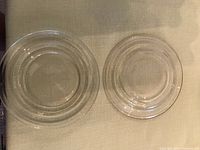 Top view of two clear glass plates showing concentric ridges on the sides and smooth center area.