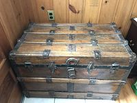 View of flat top wooden steamer trunk showing wood slats secured with metal and front latching hardware