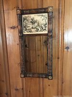 Full view of the vintage wall mirror showing the lithograph on top and mirror below, mounted on wooden wall.