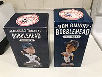 Front view of two unopened bobblehead boxes, Masahiro Tanaka and Ron Guidry editions, showing player images and names.