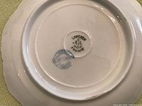 Photo showing bottom markings of Limoges A. Lanternier on cup or saucer undersides in green circles.