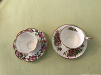 Top view of two fine china tea cup and saucer sets showing flower decoration and gold accents