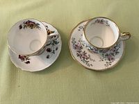 Two sets of bone china tea cups and saucers: left Tuscan pansy design and right Elizabethan pink floral design with gold trim.