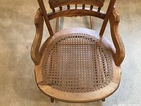 Top view photo showing the cane seat of the maple rocking chair with visible wear.