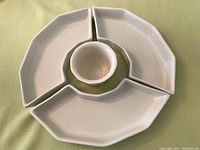 Four-piece white ceramic appetizer dish arranged in a circular pattern with three trays forming a ring and the central bowl fitting in between.