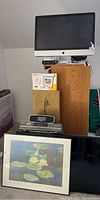 Apple iMac 26-inch displayed on a wooden cabinet with two wired mice visible and framed print leaning in front
