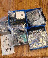 Overview of all jewelry pieces stored in small boxes and plastic bags on a wooden surface.