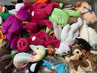 Heap of assorted colorful Ty Beanie Babies plush toys, showing variety of characters and colors with visible heart-shaped Ty tags.