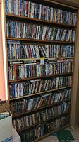 Full view of wooden shelving unit holding eight shelves of DVD and VHS cases