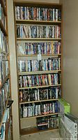 Wooden shelving filled with numerous DVD cases arranged on multiple shelves