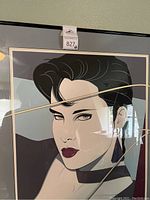 Close-up photo of the framed Patrick Nagel print showing the woman's face with scratches on the glass.