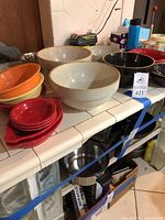 Overview of pottery bowls and colorful Fiesta ware bowls on kitchen counter showing different sizes and colors.