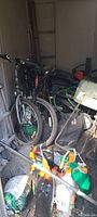 Photo showing two mountain bicycles, garden hose, wheelbarrow, watering cans, garden soil bags, and garden tools tightly packed in a shed.