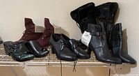 Full view of all six pairs of women's boots and shoes on a metal shelf, showing variety of styles and colors in size 9.5.