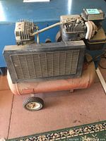 Side view of Craftsman air compressor showing orange tank, motor, wheel and grille.