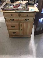 Front view of the solid pine kitchenette-sized cabinet showing five drawers and one cabinet door with antique-style handles and knobs.