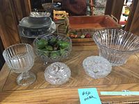 Five crystal dishes including pedestal dish, bowls and lidded candy dishes on wooden table