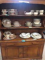 Full front view of vintage solid wood kitchen hutch with various vintage dishware displayed on shelves.