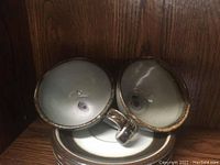 Two Mexican pottery cups placed upside down inside matching saucers, showing interior glazing and handles.