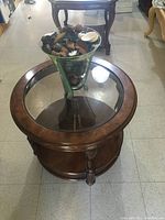 Front and top view of walnut round end table showing glass inset top, wooden finish, and lower shelf