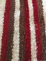 Close-up image showing the woven texture and colors of the cotton saddle blanket with red, brown, and white stripes.