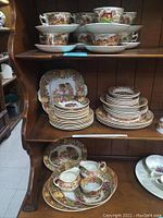 Full view of 62-piece china set featuring plates, bowls, cups, and serving pieces with detailed English Scenery design.