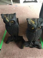 Front view of both owl andirons showing yellow eyes and feather texture