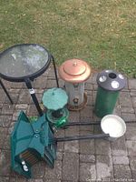 Overview of entire outdoor lot showing most items including bird feeders, green glass feeders, citronella candle, and side table
