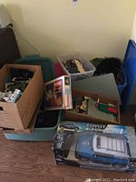 Photo showing assorted children's toys piled in boxes and containers, including boxed Ramagon 1000 set and boxed Toyota FJ Cruiser RC car.