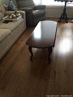Full view of the wooden drop leaf coffee table showing the closed leaf, Queen Anne style legs, and polished wood surface.
