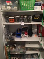Shelving unit with glass jars containing screws and fasteners, plastic bins with assorted hardware, boxes, and small toolkit items.