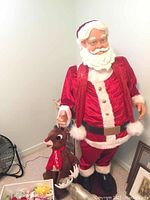 Full view of animated Santa figure in red velvet suit with attached microphone cable and plush Rudolph reindeer