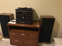 Full view of Technics stereo system components stacked on wooden stand with two tall floor speakers on each side.