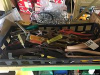 Various hand tools including screwdrivers, hammers, wrenches, and sanding blocks in a crate