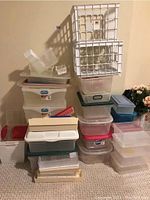 Photo showing stacked plastic totes, bins, and containers including white crate bins and various translucent boxes with lids.