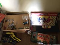 Photo showing the National Hockey League Game box and Popeyes Comic Picture Puzzle box along with some aqua launchers and game parts like goal nets and players.