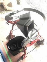 Folding walker folded showcasing adjustable handles and structure; two black plastic lifts placed in walker pouch