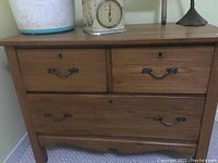 Front view of wooden washstand showing three drawers with metal handles.