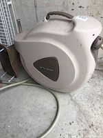 Main view of beige Flo Master water hose reel with handle and attached hose on concrete floor.