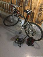 Full view of bicycle leaning against wall with both helmets on floor