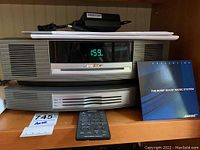 Front view showing main unit and multi-CD changer stacked, remote control at front, owner’s manual and power adapter on top