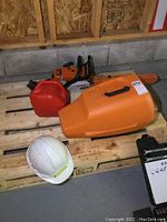Overview showing chainsaw, fuel can, carrying case and hard hat