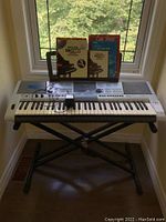 Full view of Yamaha E403 keyboard on X-style stand with sheet music on built-in holder by window.